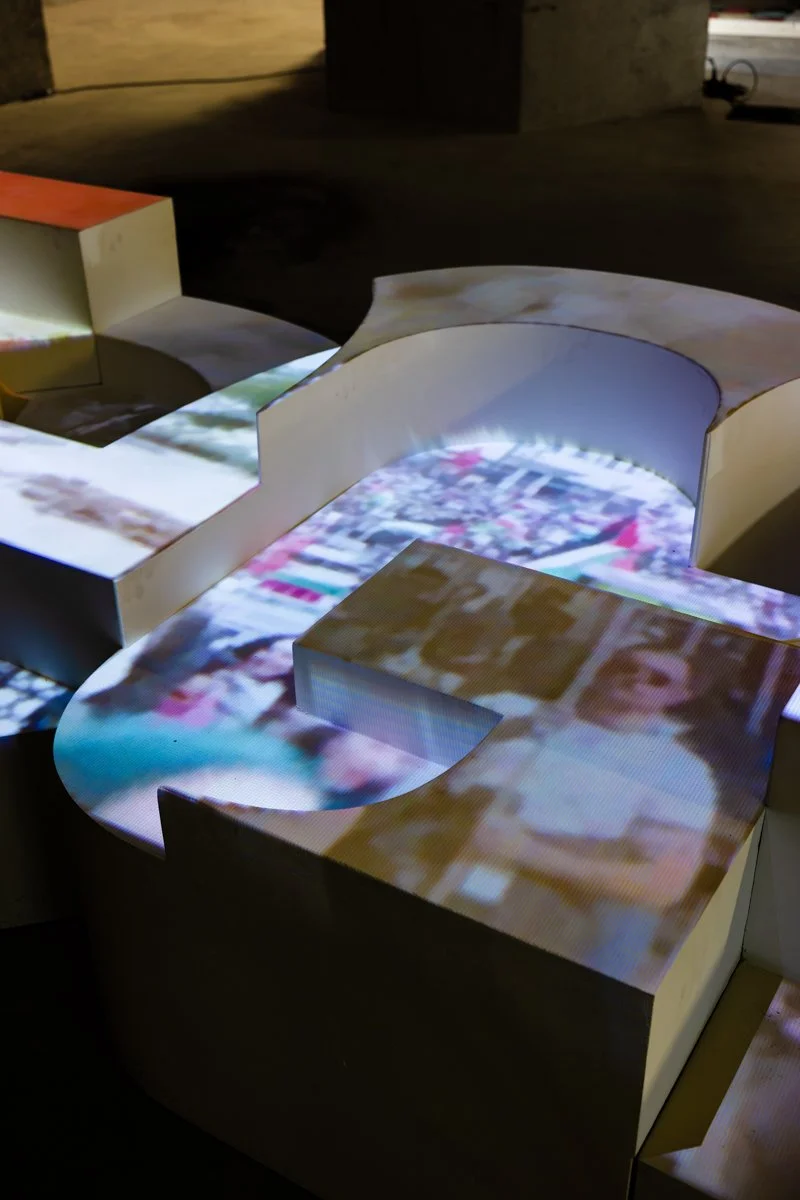 Close-up of Saïd Kinos’ Legacy_v2, showing projected imagery layered across the surface of the sculptural text.