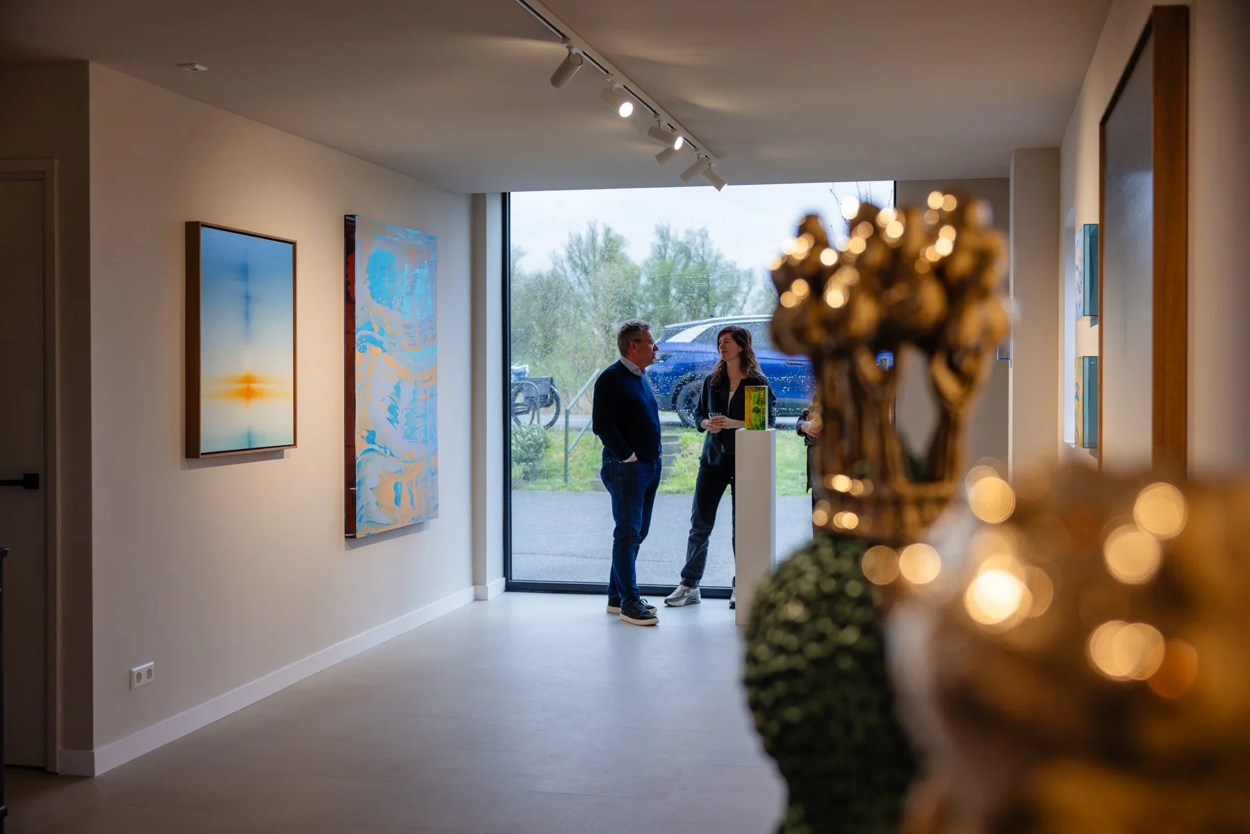 Visitors in the gallery based in Krimpen aan de Lek talking, surrounded by artworks from Jeske Haak, Lisette Schumacher and Donald Schenkel