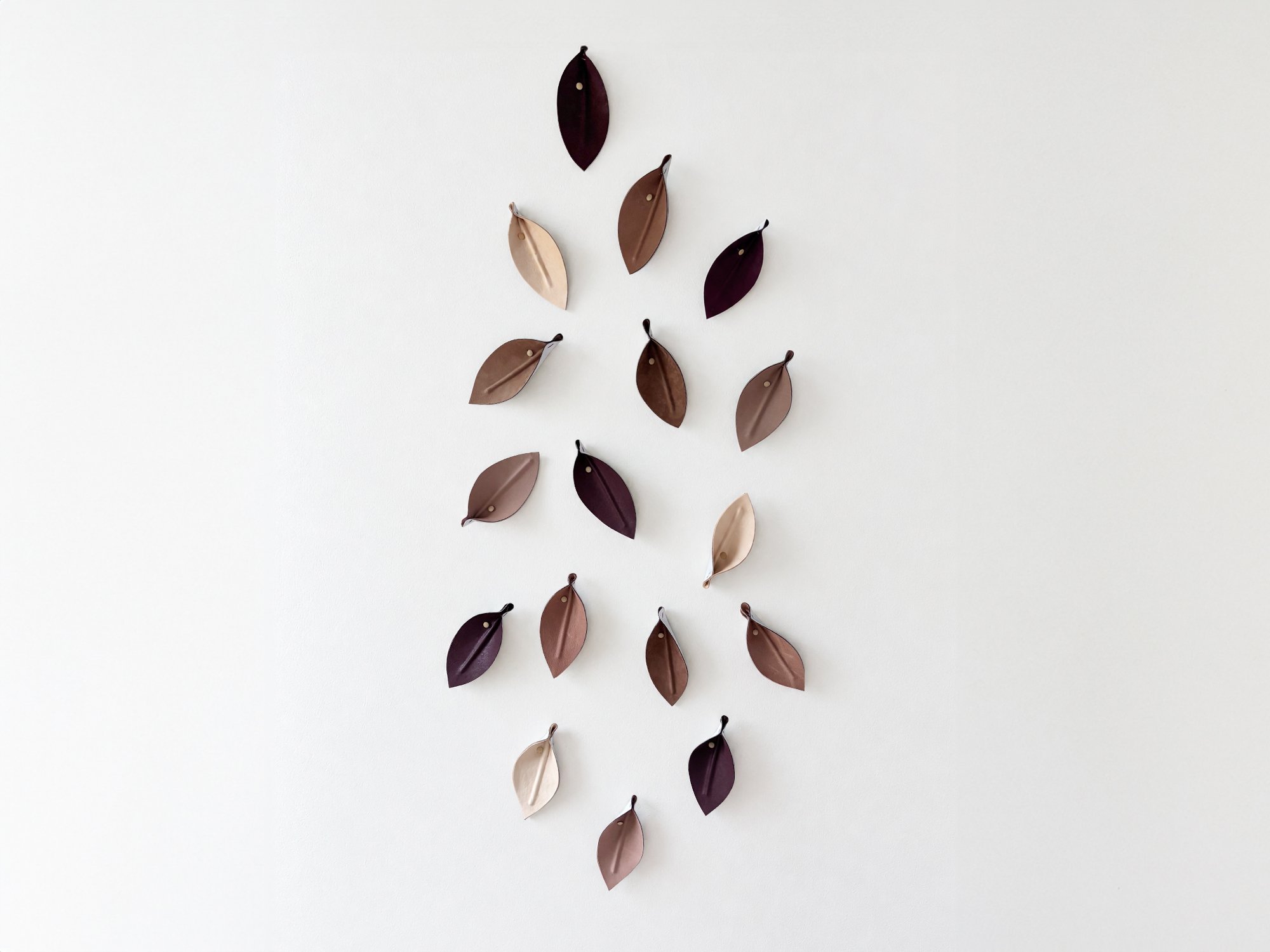 Leaves Neutrals by Madelon Uljee, a wall sculpture of individually shaped leather leaves in muted blush, taupe, brown and plum tones.