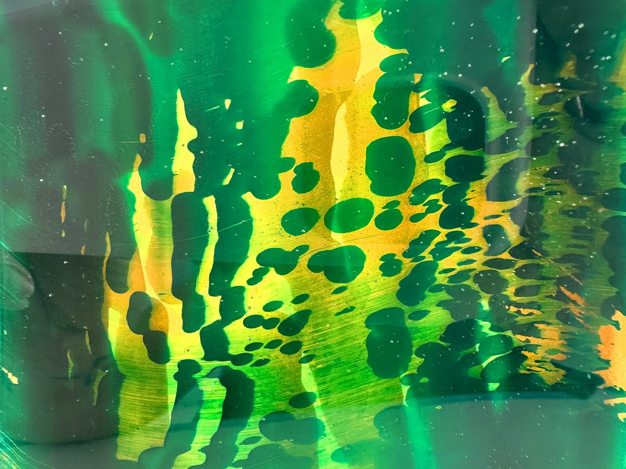 Detail of green and yellow handcast glass sculpture by Lisette Schumacher showing light reflections in transparent glass