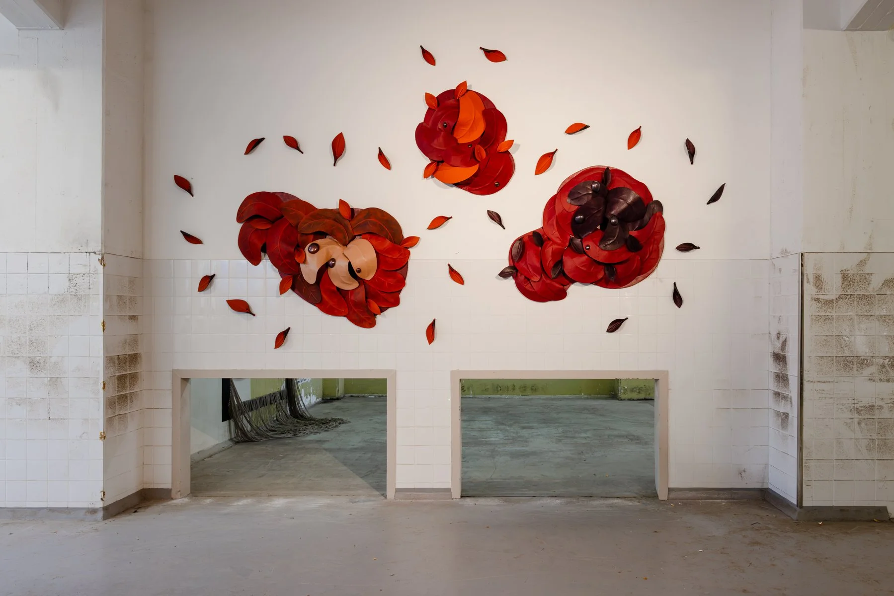 Front view of After the Storm by Madelon Uljee, a large wall installation of layered leather sculptures and individual leaves in red, burgundy and orange.