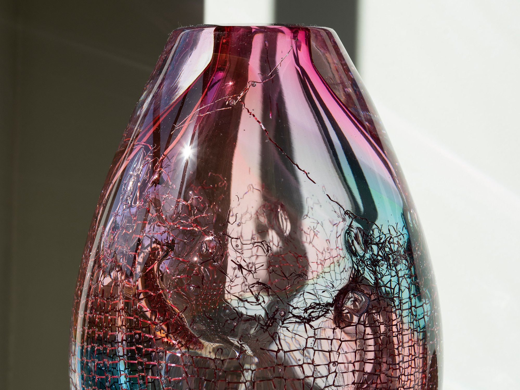 Detail of Francisca Snel's pink glass sculpture showing transparent layers, subtle green tones and copper mesh.