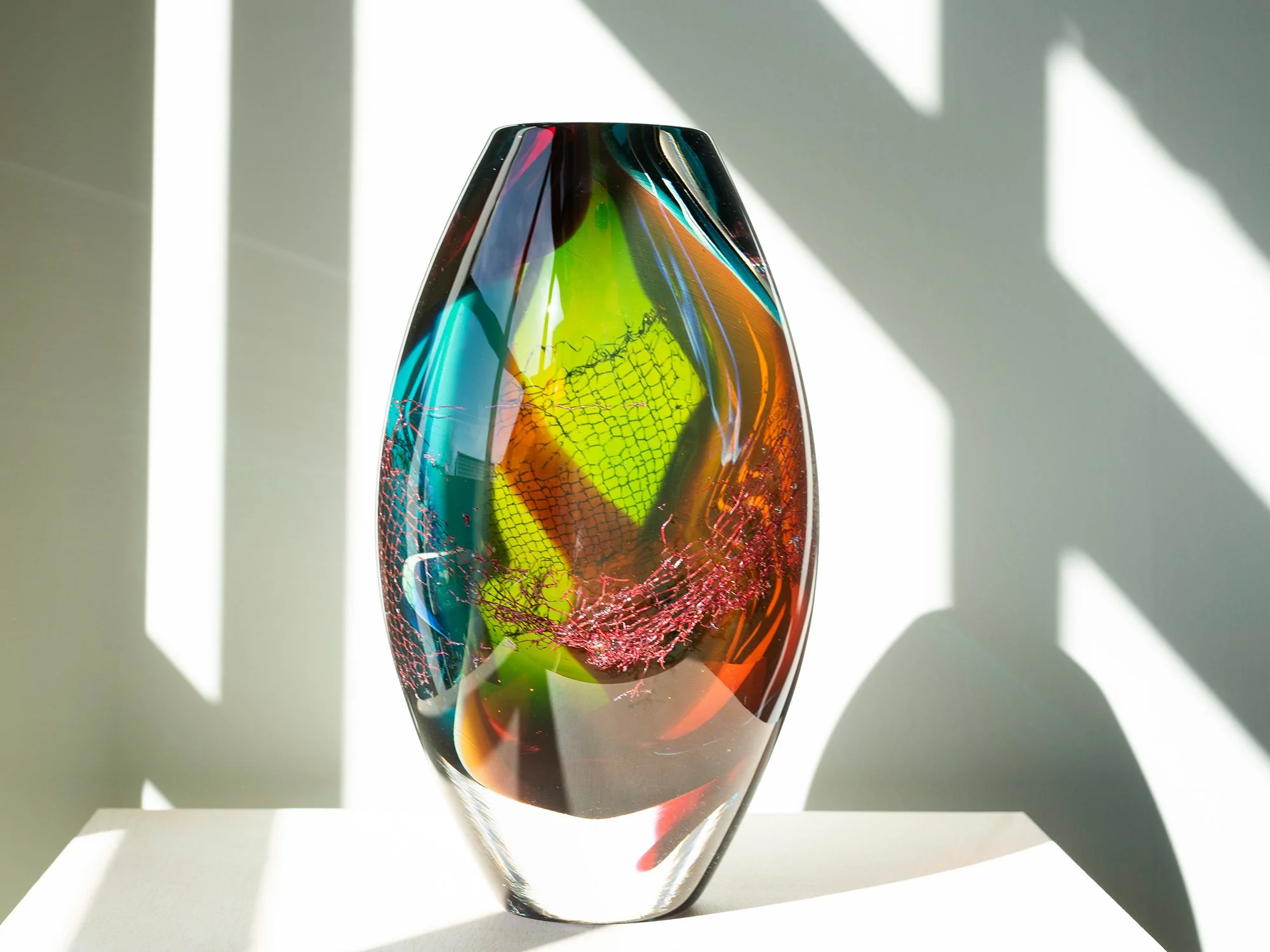 Sideview of colourful blown glass sculpture by Francisca Snel showing layered glass and copper