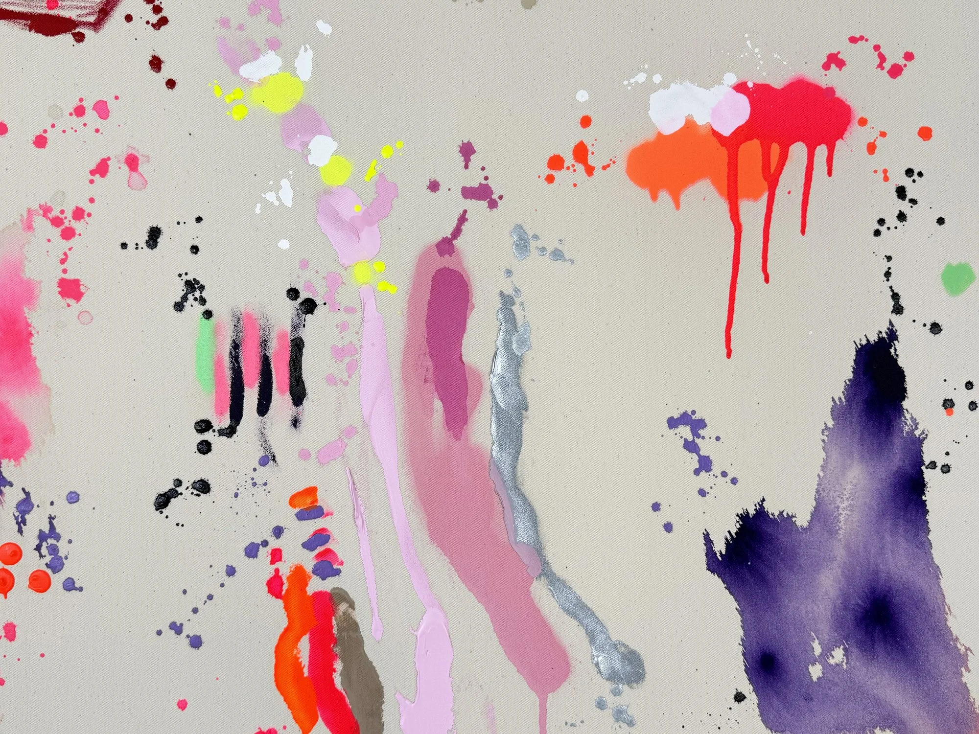 Detail of expressive pink and yellow paint splashes spreading into raw canvas