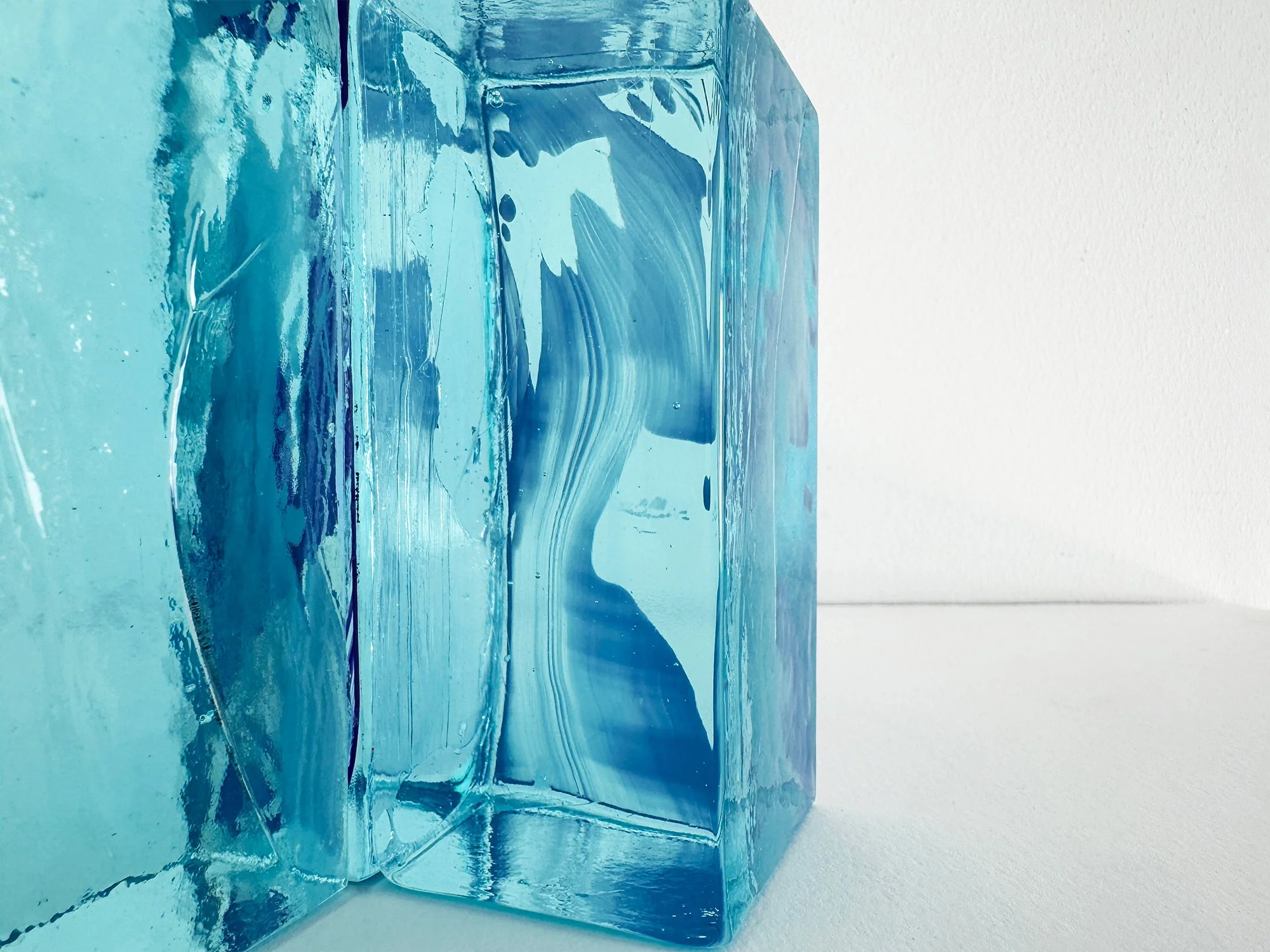 Close-up of translucent glass sculpture showing layered blue pigments and internal depth