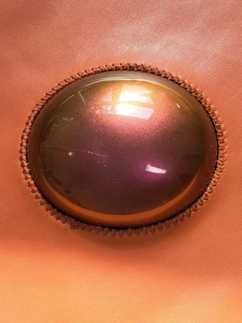 Detail of a handcrafted leather wall sculpture by Madelon Uljee, showing iridescent surfaces and intricate stitching.