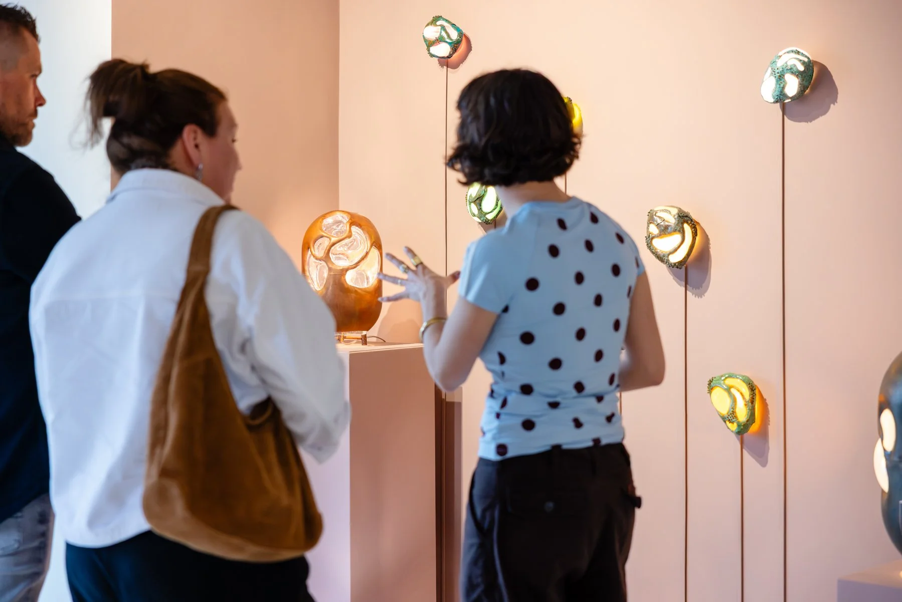 Anna Oudhof speaking with visitors about her glass and copper sculptures in Root Gallery, contemporary sculptural works combining material and process