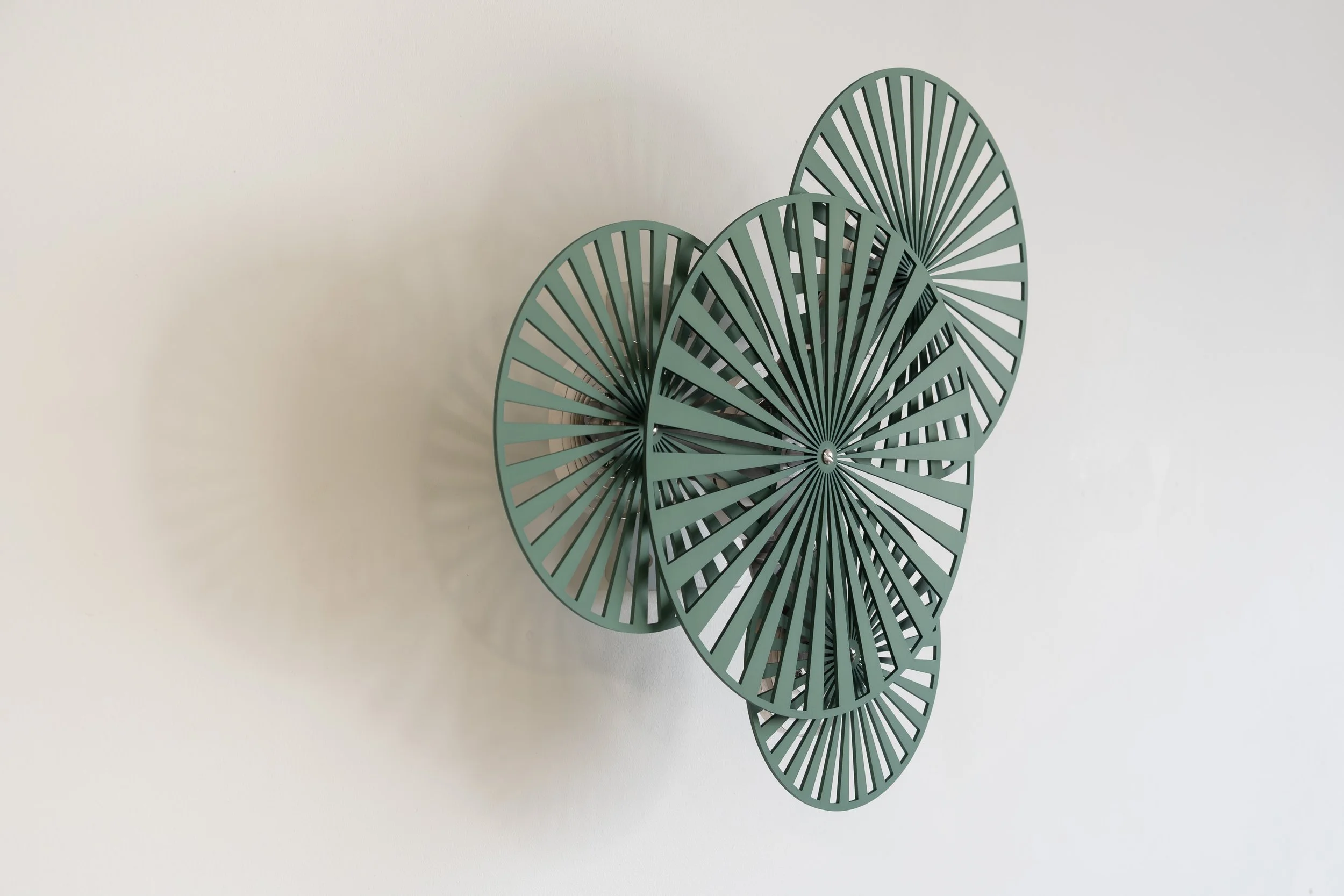 Interactive kinetic artwork by Freerk Wilbers in green anodised aluminium, featuring four mechanically connected circular elements.