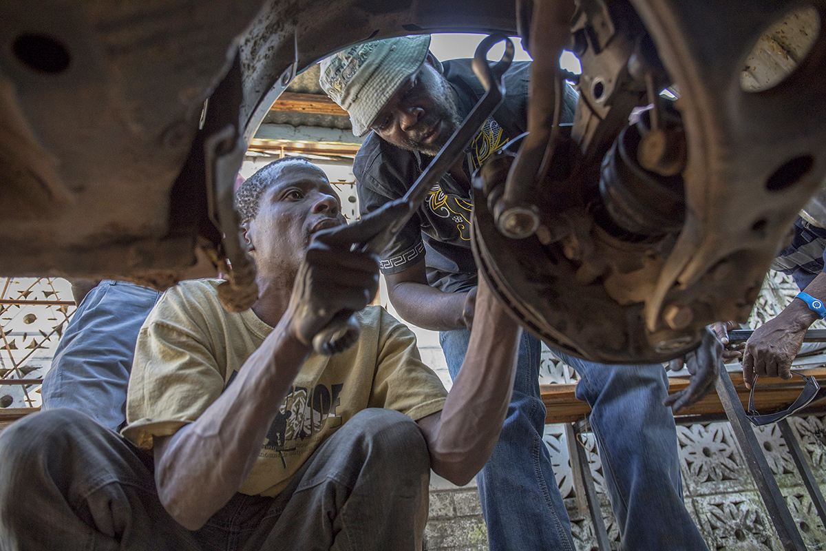 Patmos Masocha, (41) runs a garage in Mashawa with his friend and business partner Witness, who he met when both were in VSO-supported vocational training while serving sentences in Mutimurefu Prison. Here Patmos helps a young intern at his garage to repair a car. - VSO International UK