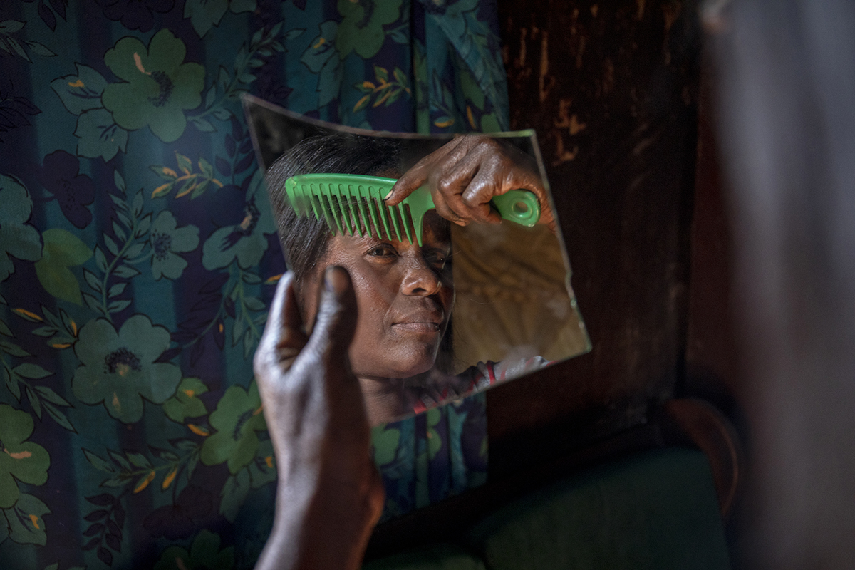  Roselyn Ngona, a farm worker at a horticulture farm, looks in the mirror while preparing herself to go out after work at the farm.  - For HIVOS  