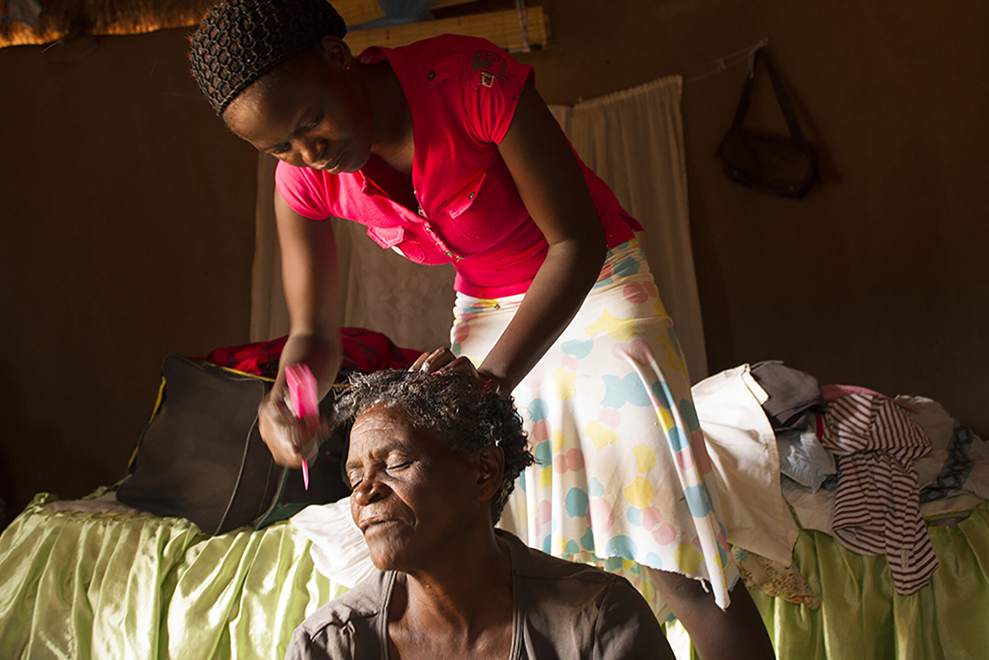  December 16, 2014: Matron (21), Gogo Mpofu's oldest granddaughter, does her grandmother's hair at their rural home in Nkayi. "In the old days, when I was younger, I always enjoyed straightening my hair. Now my grandchildren always make sure that I l