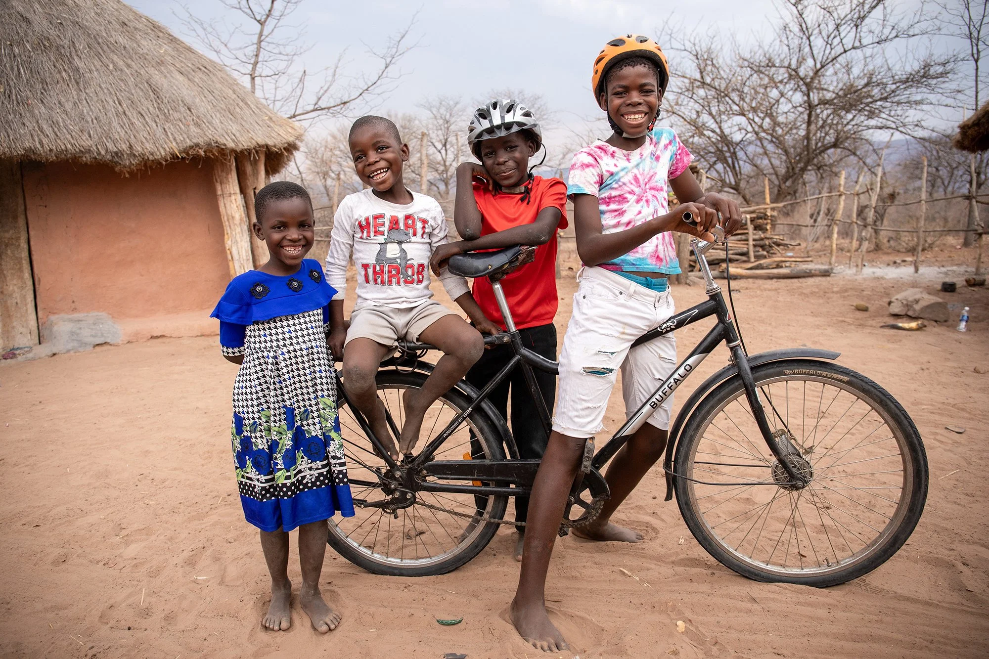 Brothers Chabota (6) and Forgive (14) share a moment with their cousins Bubota (girl) at their home in Chininga, Binga, Zimbabwe. Chabota, Forgive and Bubota were treated for active trachoma. - For Sightsavers UK