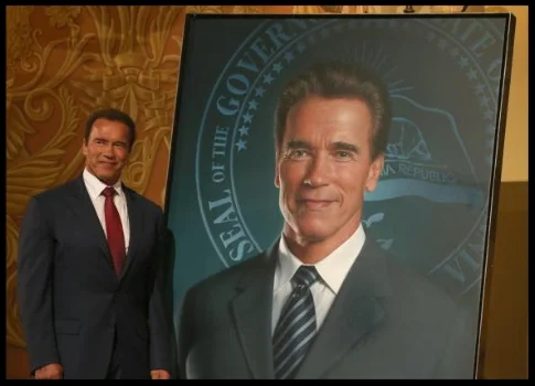  Former California Gov. Arnold Schwarzenegger poses next to his portrait. (Photo by Justin Sullivan/Getty Images)