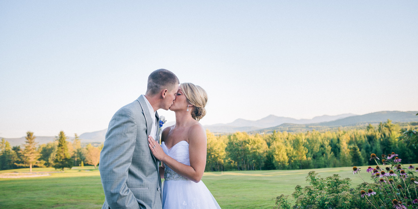 NH Wedding Photographer: groom kissing bride in the mountains