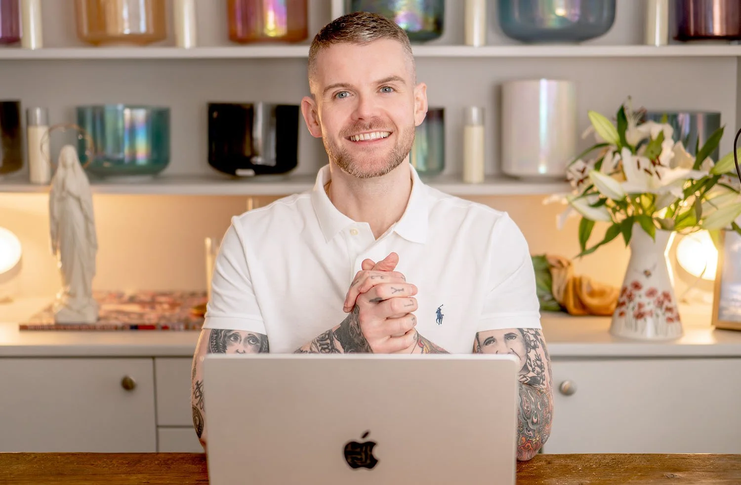 A photo of Kyle Gray sitting at a desk smiling with his laptop open