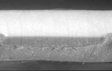 Manufacturers of high-quality PVC formulate and build a roofing membrane with a monolithic top ply. Because these higher-performance membranes contain up to 50% more anti-weathering ingredients in the top ply, they are able to offer a higher degree of protection and improved performance over a longer period of time. Below is one such membrane. Note the significant increase in top ply thickness, the monolithic nature of the top ply, and the equal thicknesses of the top and bottom plies.