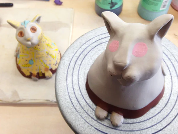 The cats getting decorated. First comes the white slip, then the underglazes are applied. 