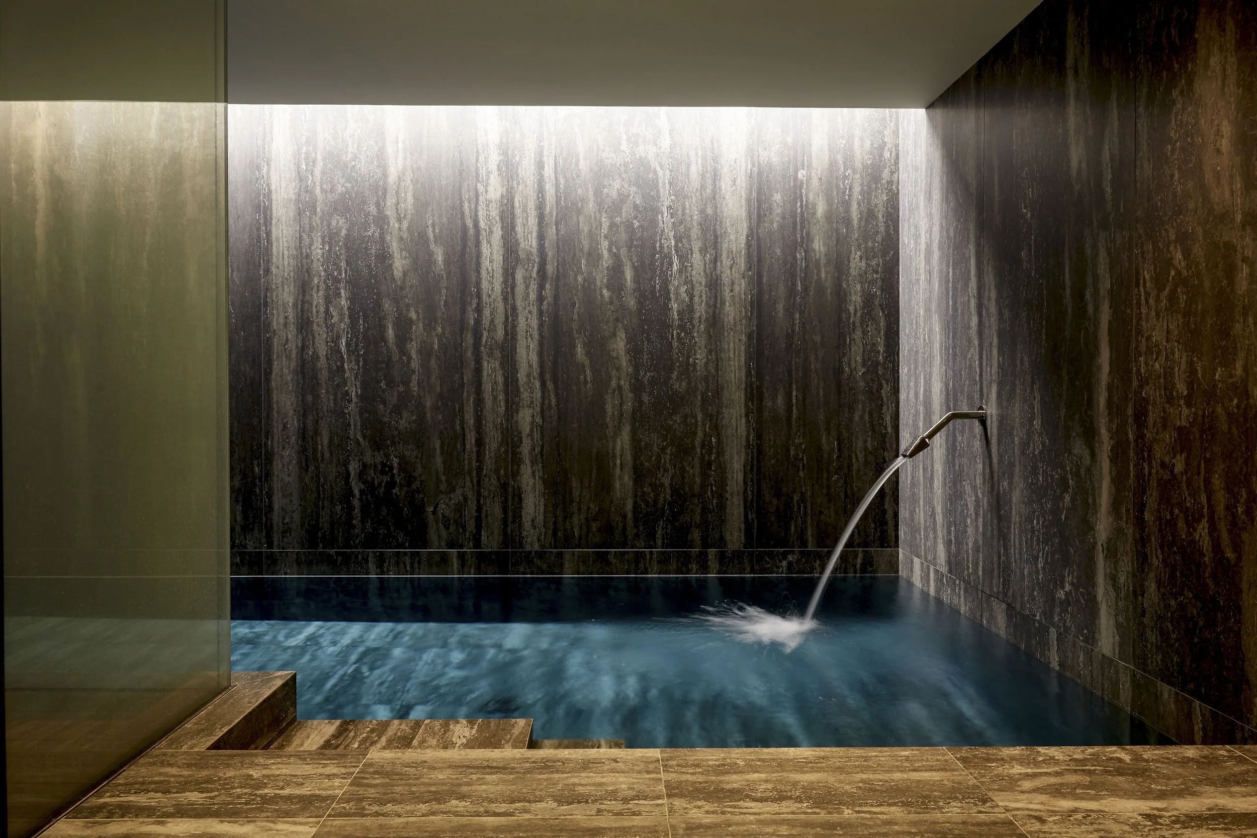 Basement swimming pool with stone walls and water feature in luxury Chelsea townhouse renovation
