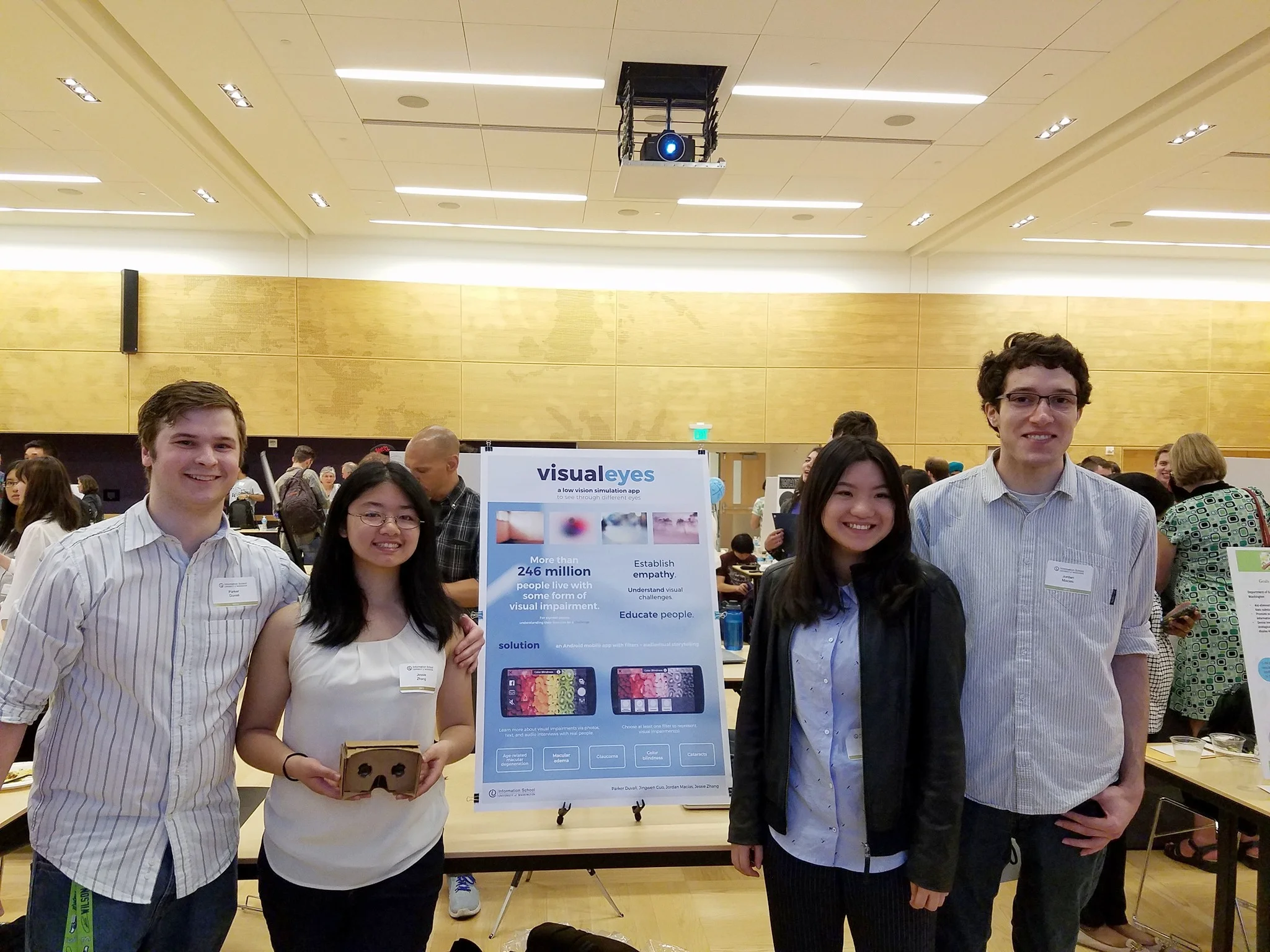 My team and I smile with our Google Cardboard and poster at Capstone Night. We are all wearing blue and white.