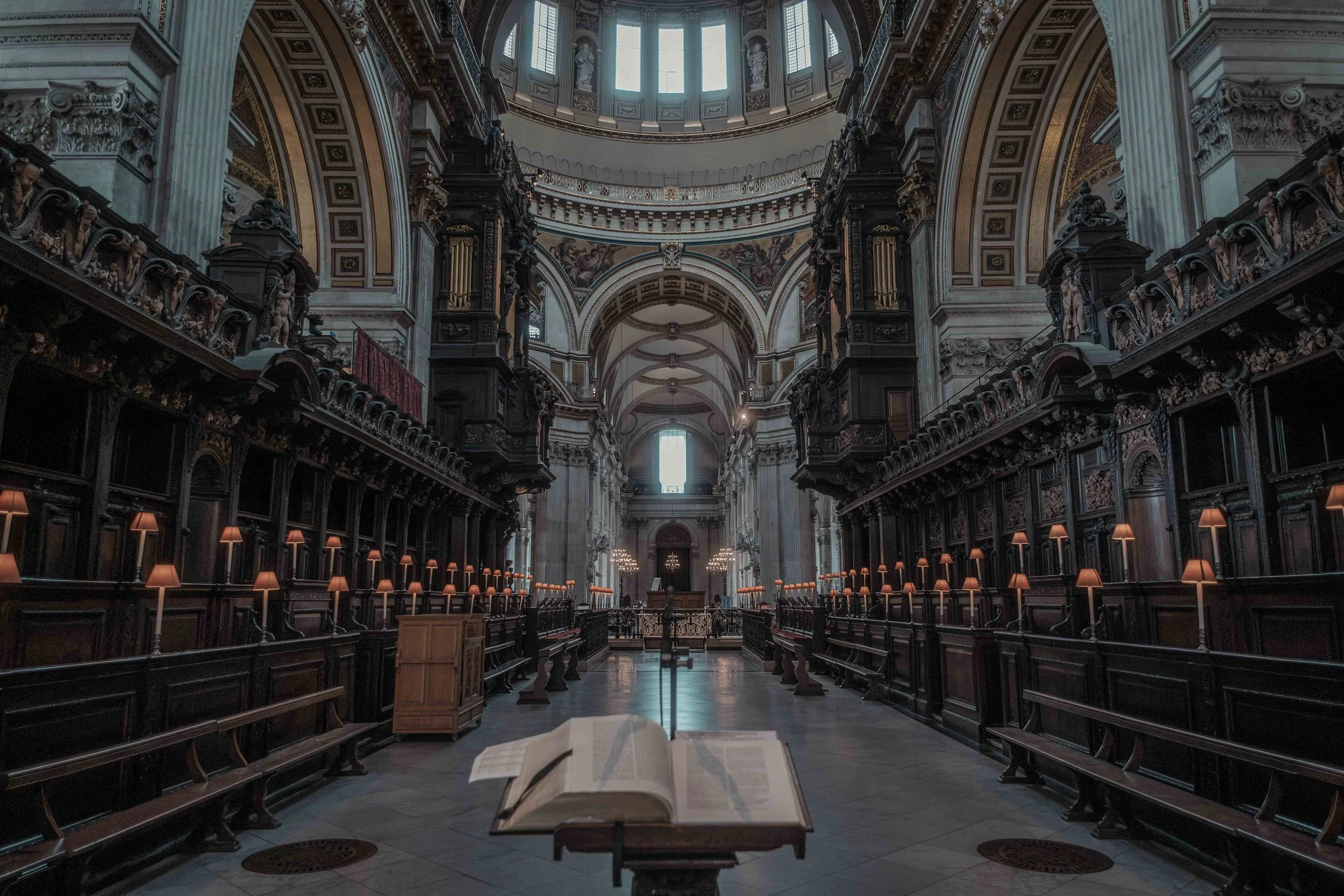 The Quire inside St Paul's Cathedral, showing carved wooden choir stalls beneath the cathedral's decorated arches.