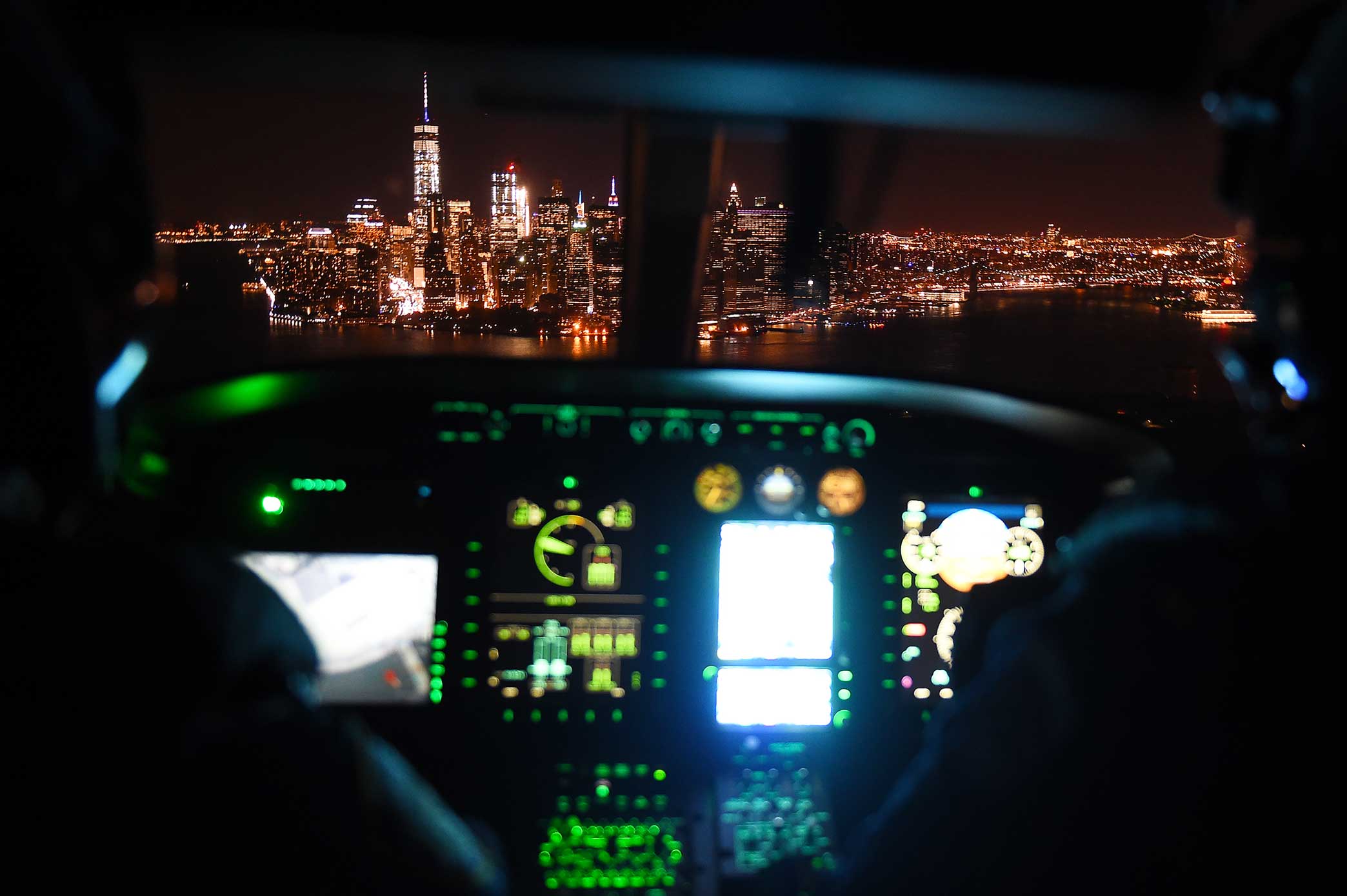 Officers with NYPD’s Aviation Unit pilot their helicopter towards a stunningly lit Manhattan skyline after participating in a 5 Borough tour for National Night Out Against Crime.