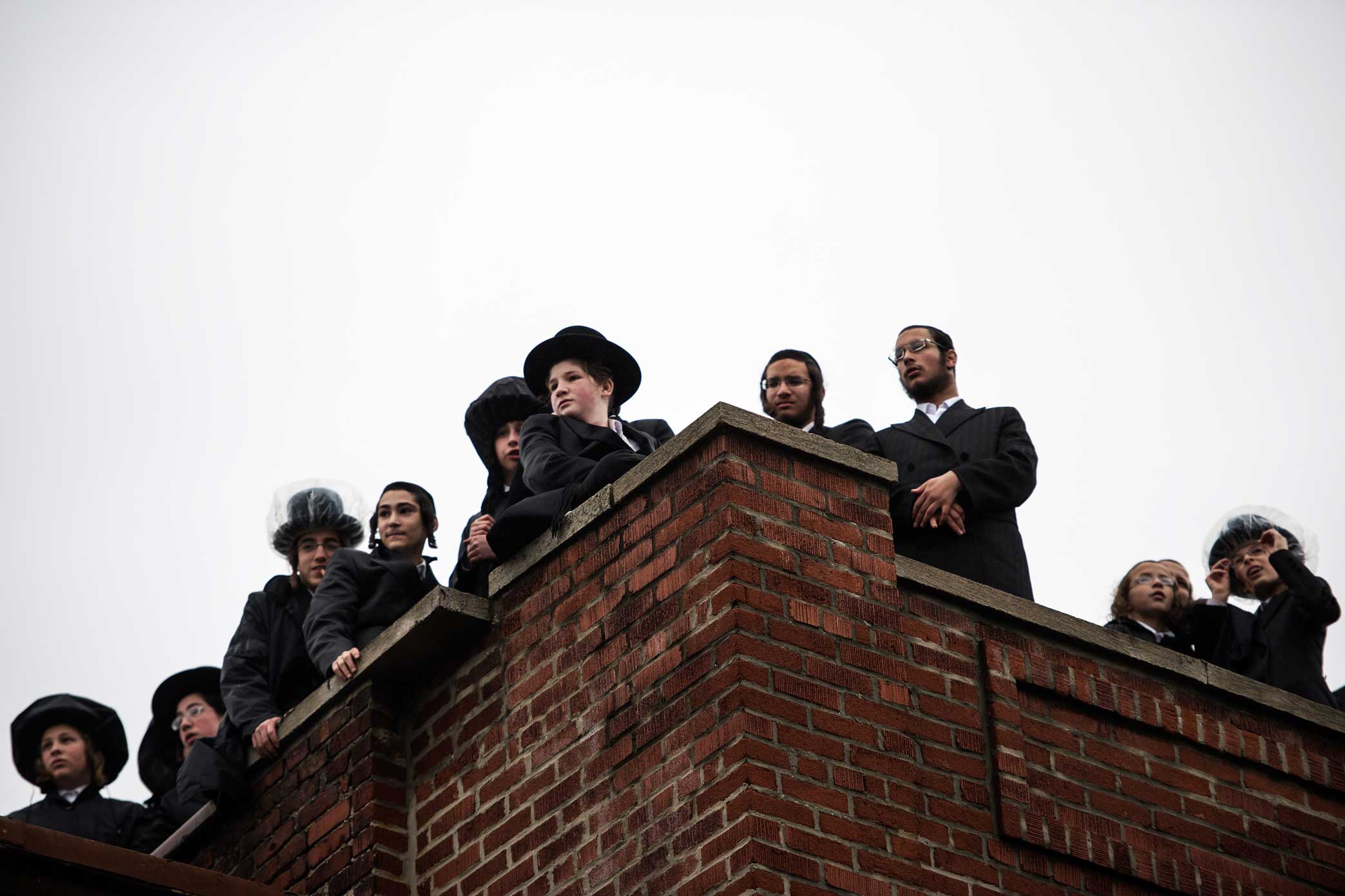 Community member watch from the roof top of their Synagogue as the New York City Fire Department work to put out flames caused by a gas explosion at a three-story building in the Borough Park section of Brooklyn.