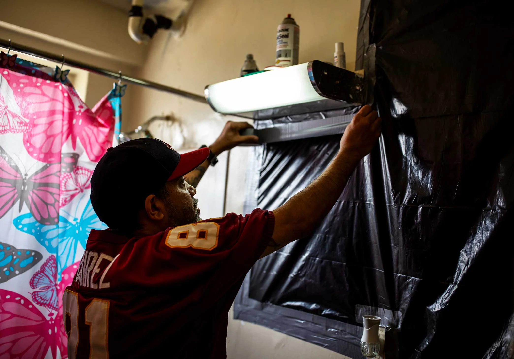 A worker left a hole open and pipe leaking in the Ramirezes’ bathroom wall after coming to repair the mold. Here, Juan Ramirez tapes trash bags over the hole to try to stem the smell of mold.