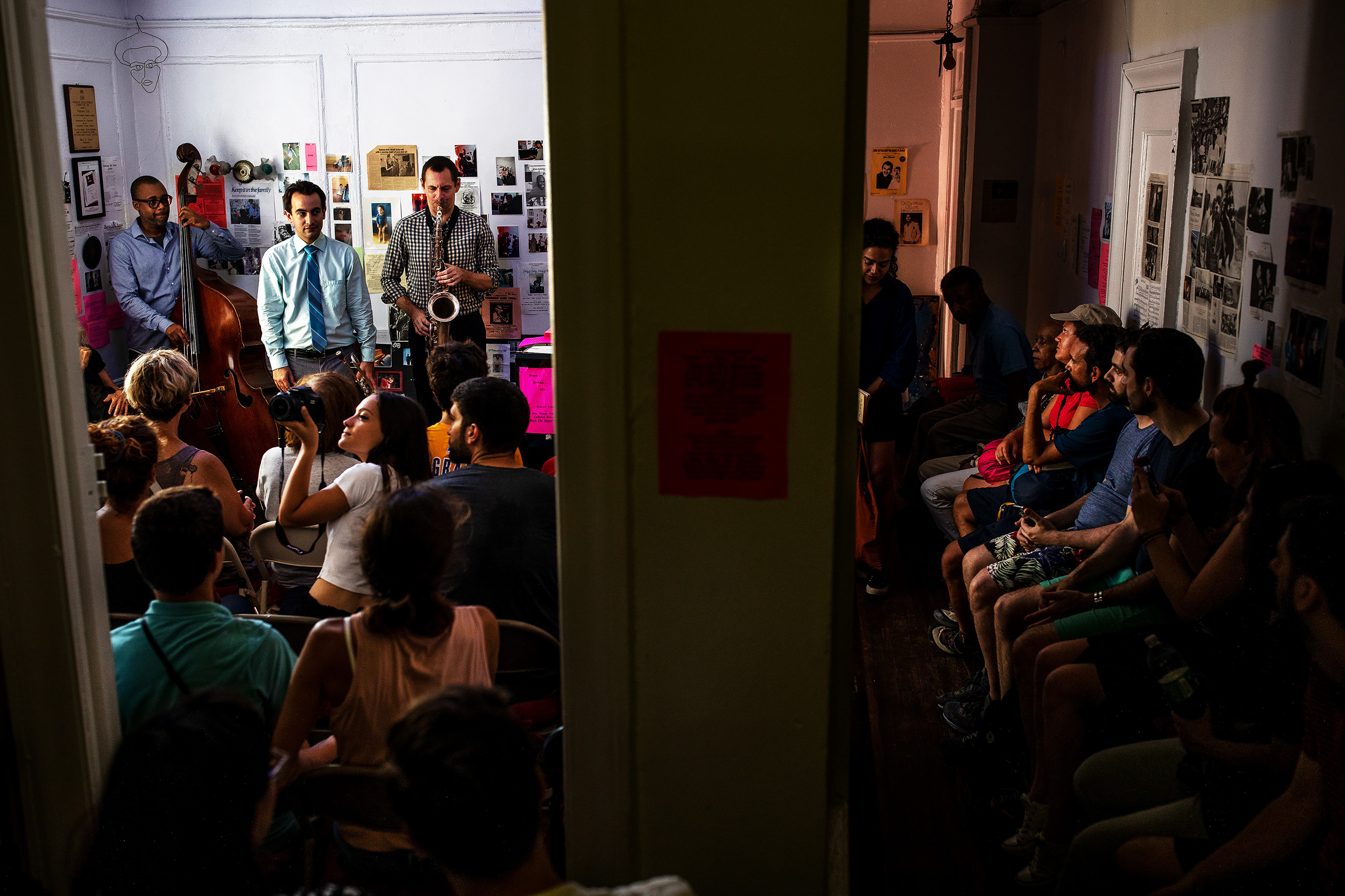 Visitors sit in the hallway and kitchen of Marjorie Eliot's apartment listening to live jazz music during Marjorie's weekly jazz show in Manhattan, New York. Every Sunday for more than a decade a jazz concert has taken place in the parlor of Marjorie Eliot's home on what she calls the northern tip of Harlem. Her weekly free concerts in the living room of her apartment are legendary in Harlem and an institution for jazz lovers citywide.