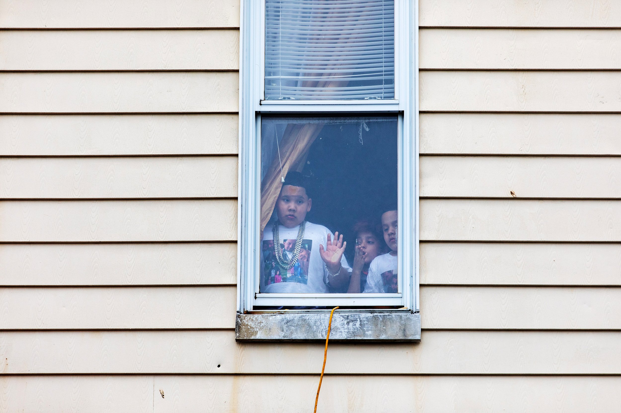  Locals watch from inside as NYPD officers investigate a 911 call regarding individuals breaking social distance rules at an outdoor street cookout during the Covid-19 Pandemic in Brownsville Brooklyn, New York.    