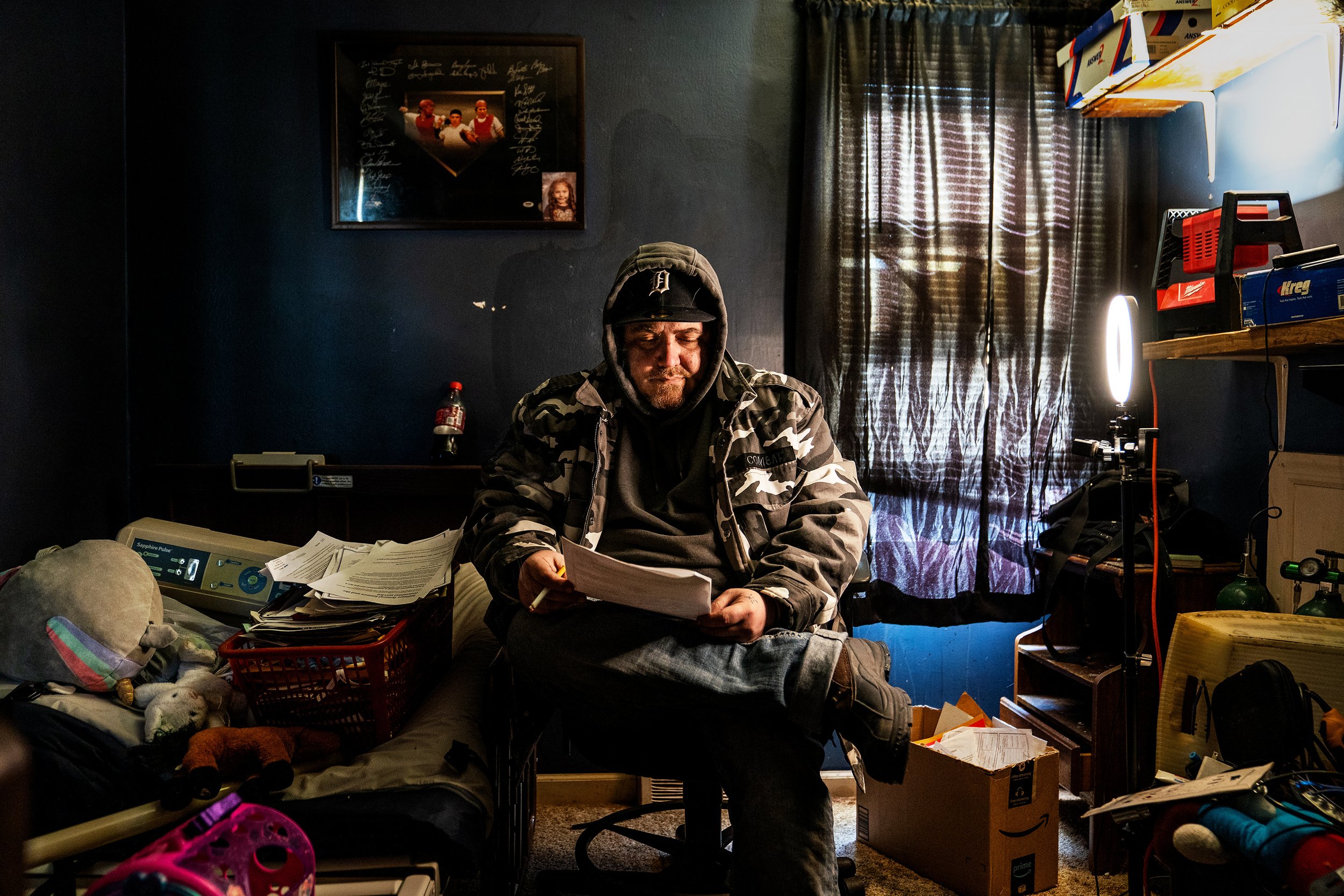  David Ramsey Jr, 39 smokes a cigarette while siting in his fathers room reviewing documents and bills at his home in Lincoln Park, Michigan. “So hard to believe he is gone”, said David. The room remains the same with his fathers belonging.   David’s