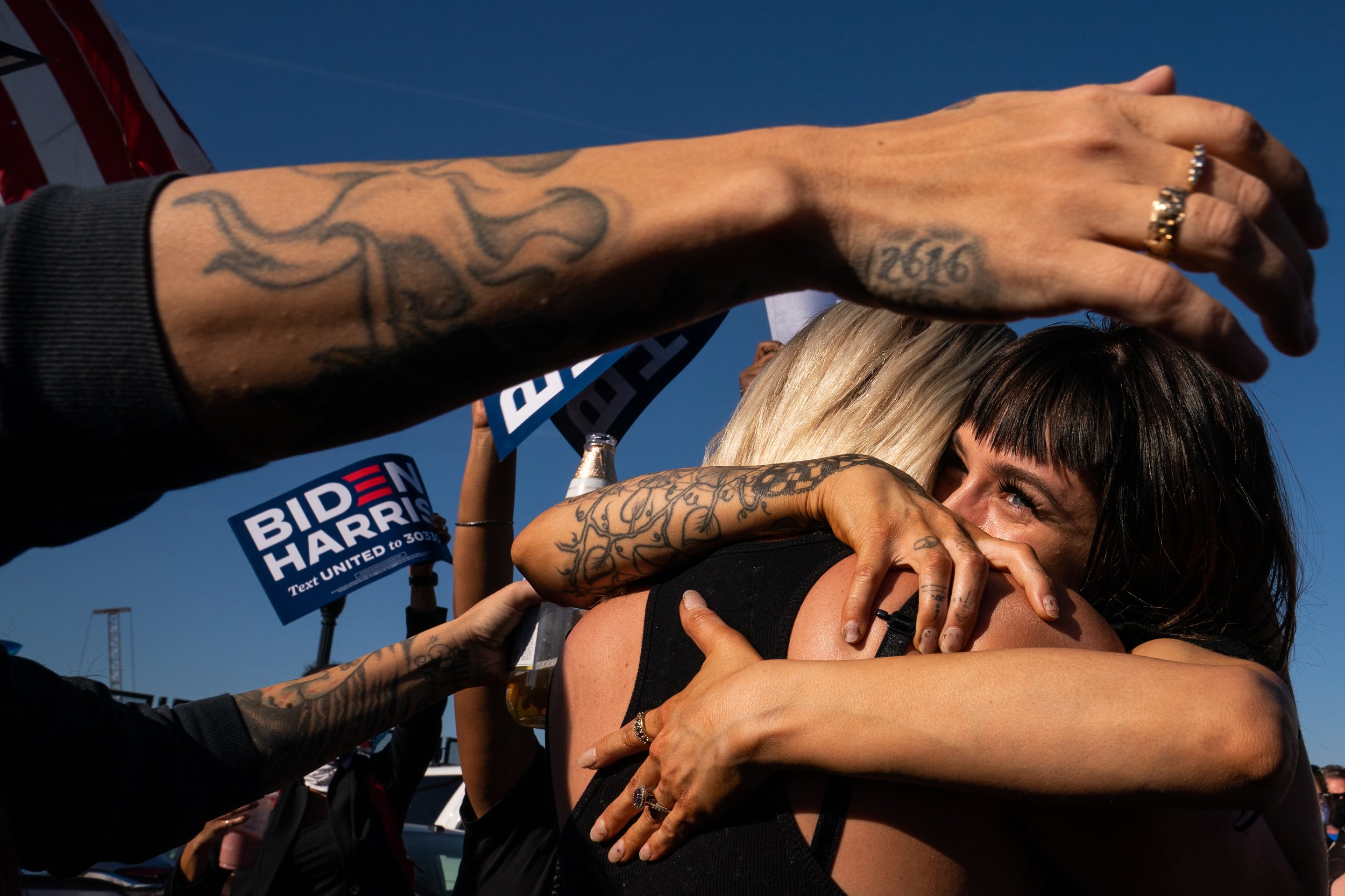  Supporters embrace each other while celebrating President-elect Joe Biden’s presidential victory in the parking lot at the Chase Center in Wilmington, Delaware. 