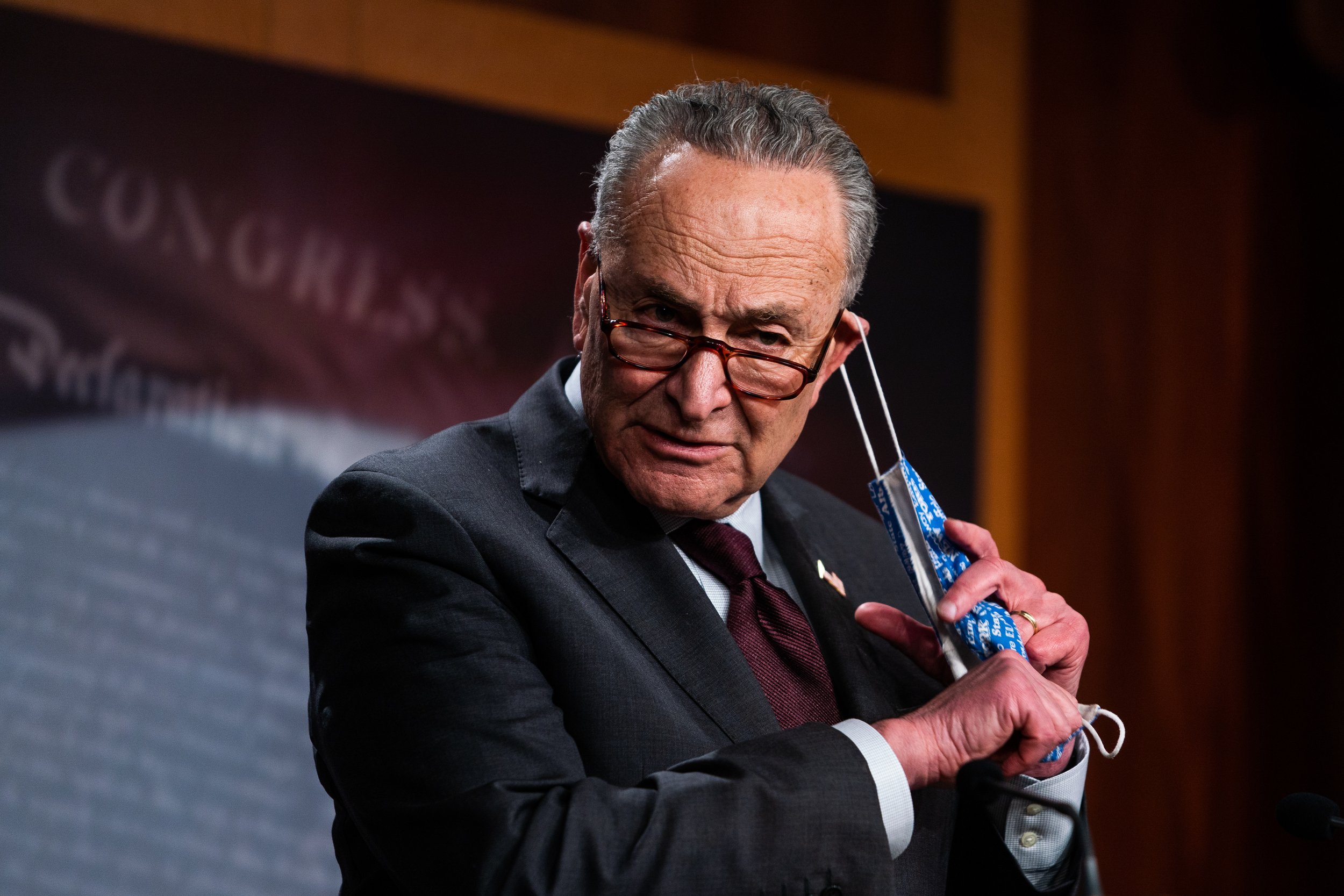  Senate Majority Leader Chuck Schumer (D-NY) removes his mask during a press conference after a meeting with Senate Democrats at the U.S. Capitol. 