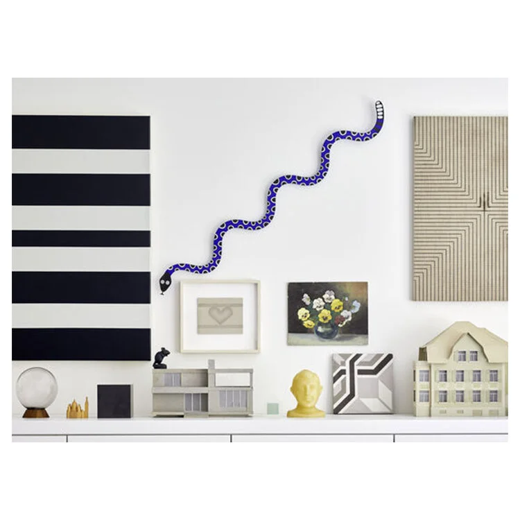 Sculptural metal wall piece featuring Girard’s playful snake motif with symbolic meaning.