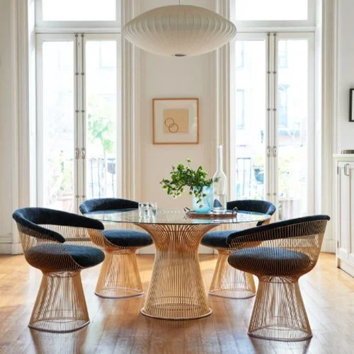 Luxury upholstered armchair with welded wire base and soft neutral fabric.