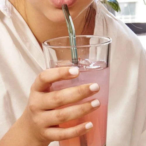 Modern kitchen scene with Kikkerland reusable glass straws displayed on a white counter.