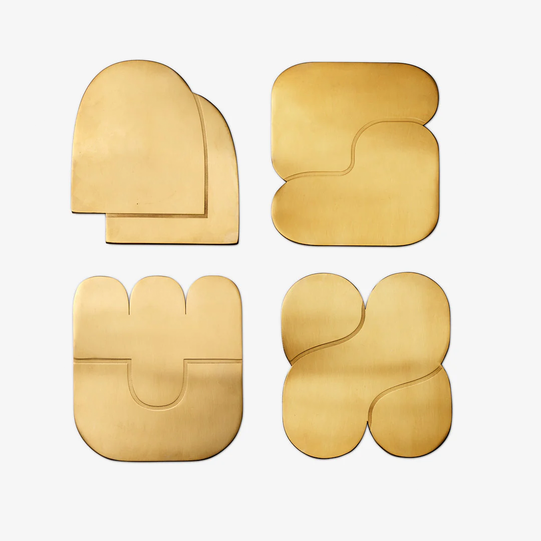 Modern geometric coasters in stainless steel with brass finish, designed for sculptural tabletop displays.