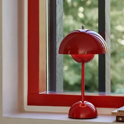 Rechargeable red table lamp with sculptural form and soft ambient lighting.