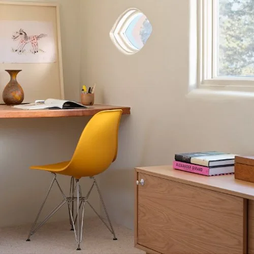 Bold yellow plastic chair with sculptural wire base and matte finish.