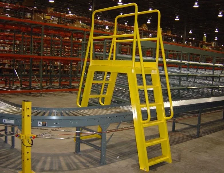 A yellow SAFE-T-FAB crossover bridging a roller conveyor line in a distribution warehouse.