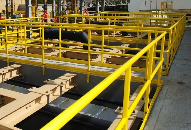 A yellow SAFE-T-FAB guardrail and gate system along the edge of an elevated industrial deck.