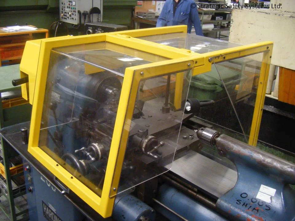 A yellow-framed SAFE-T-FAB machine guard with clear panels fitted over the working area of a lathe.