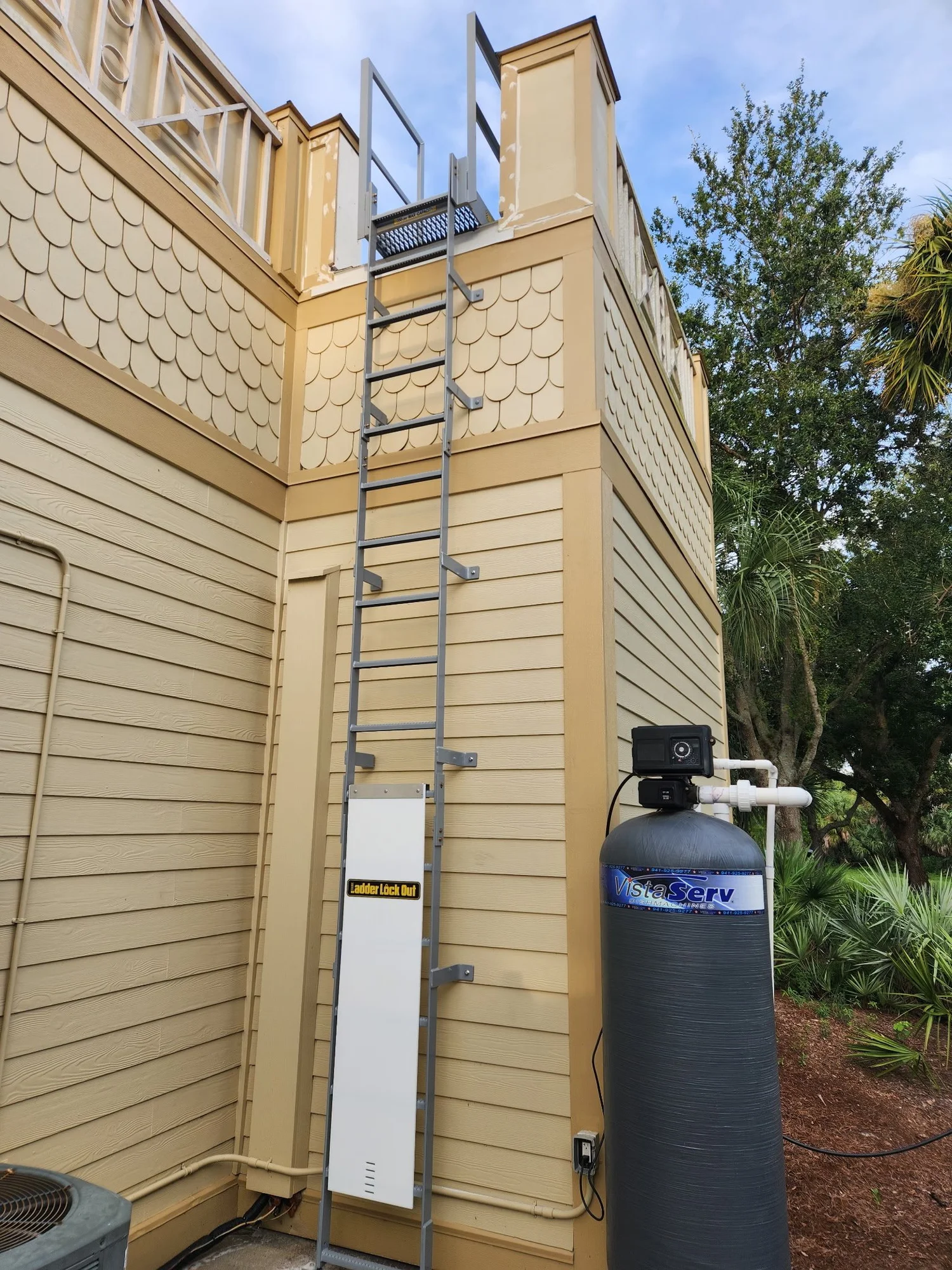 An aluminium SAFE-T-FAB fixed ladder mounted to the exterior of a building, running up to roof level without a cage.