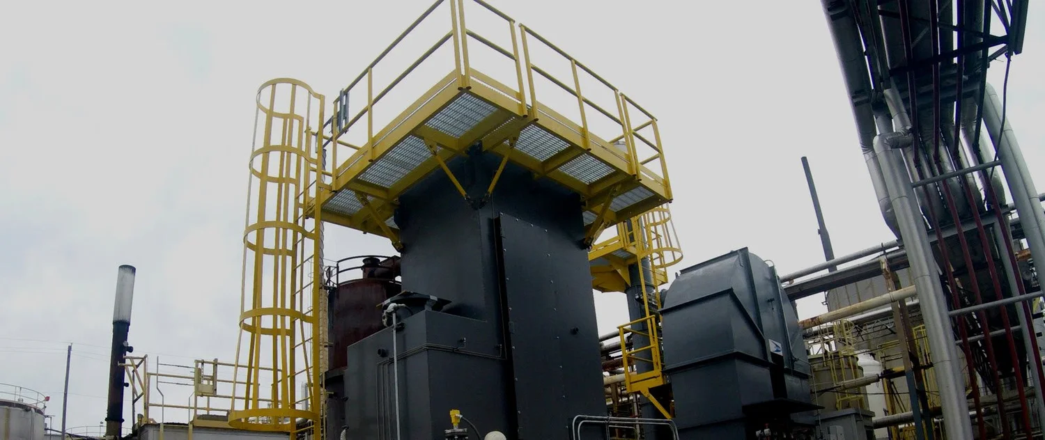 A yellow SAFE-T-FAB fixed steel access platform and stair installed around process vessels at an outdoor industrial plant.