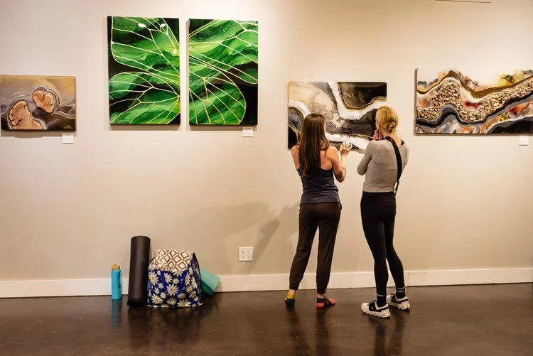  Anne Shackelford and a friend pause to take in the details of her original artwork following an immersive soundbath experience. A candid moment of reflection and connection, where visual resonance continues to ripple through conversation and presenc