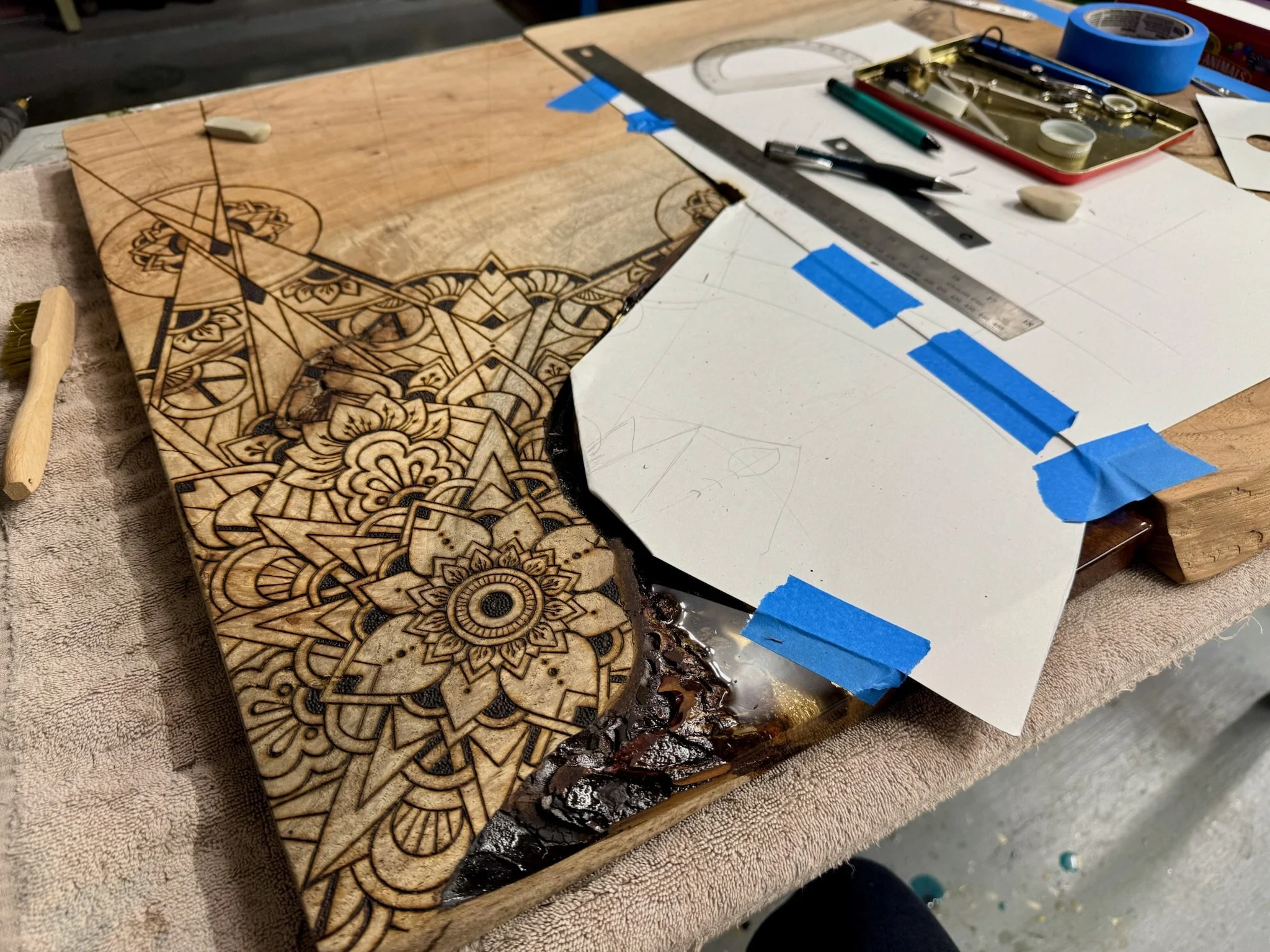  A work in progress on Anne Shackelford’s studio table, showing the precision and planning involved in her wood burned art. Layers of geometric and organic designs begin to emerge on the Texas wood panel. 2025. 
