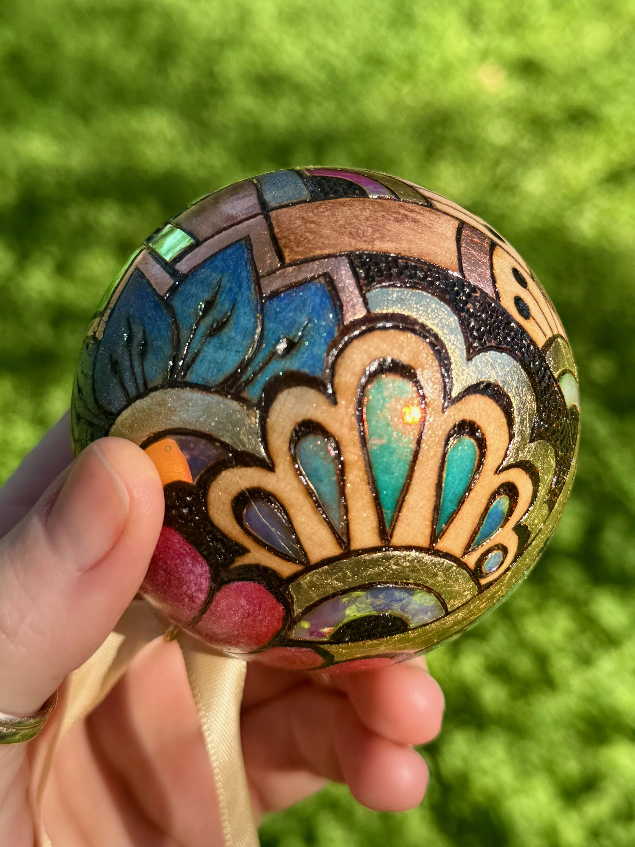 Small-scale artwork from Chrysalis Austin, radiant sphere layered with gilding and holographic film.