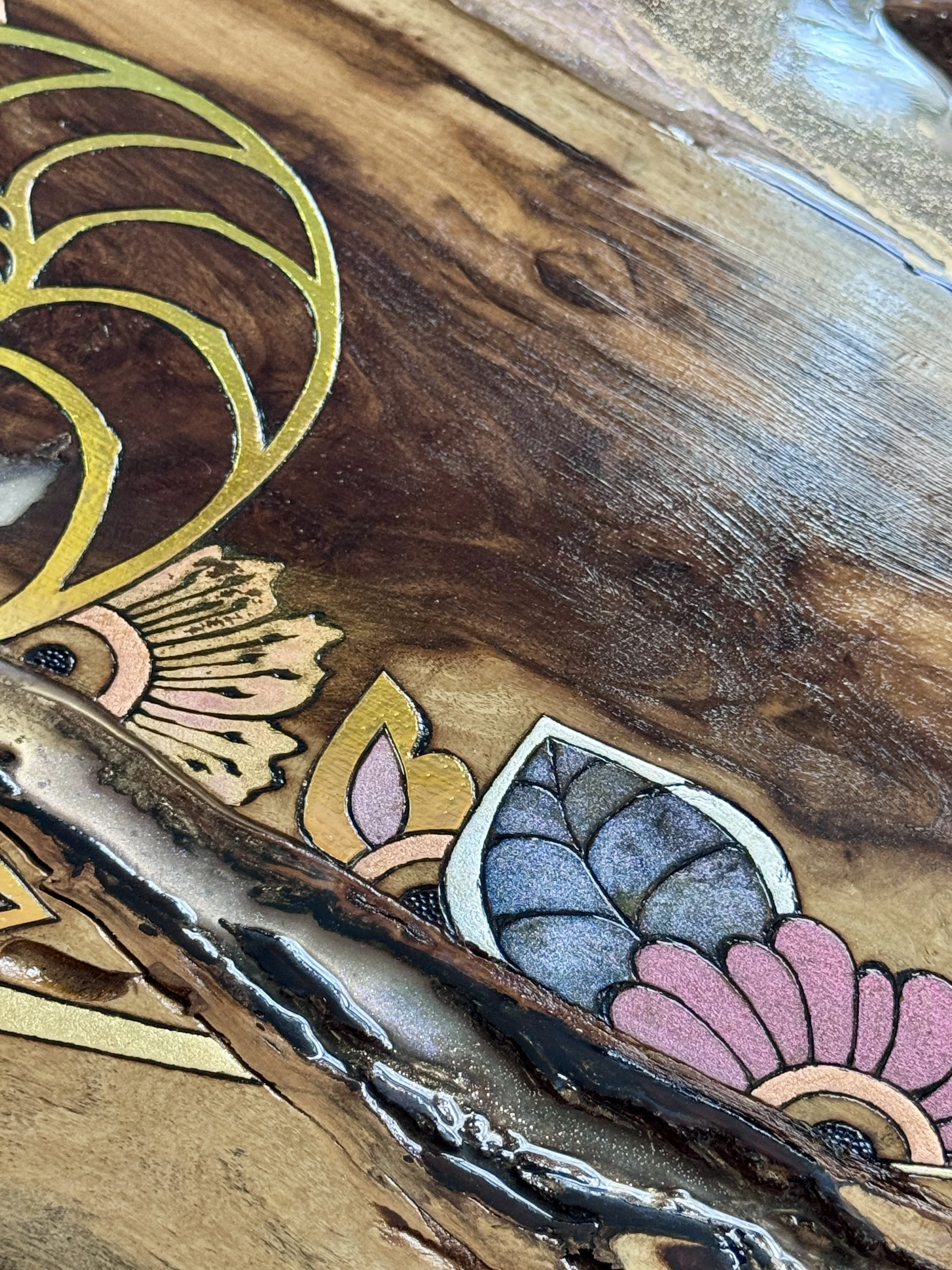 Detail of layered botanical forms, pyrography and reflective elements across the dark natural grain of the wood.