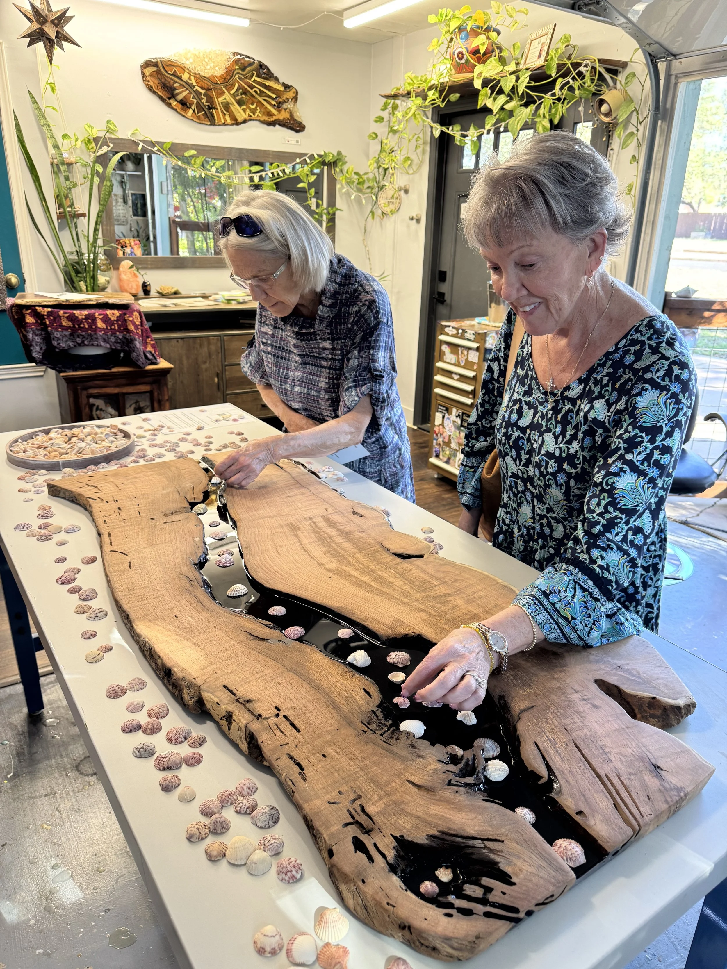 Friends and family take part in building The Collective Current by placing shells into the evolving surface.