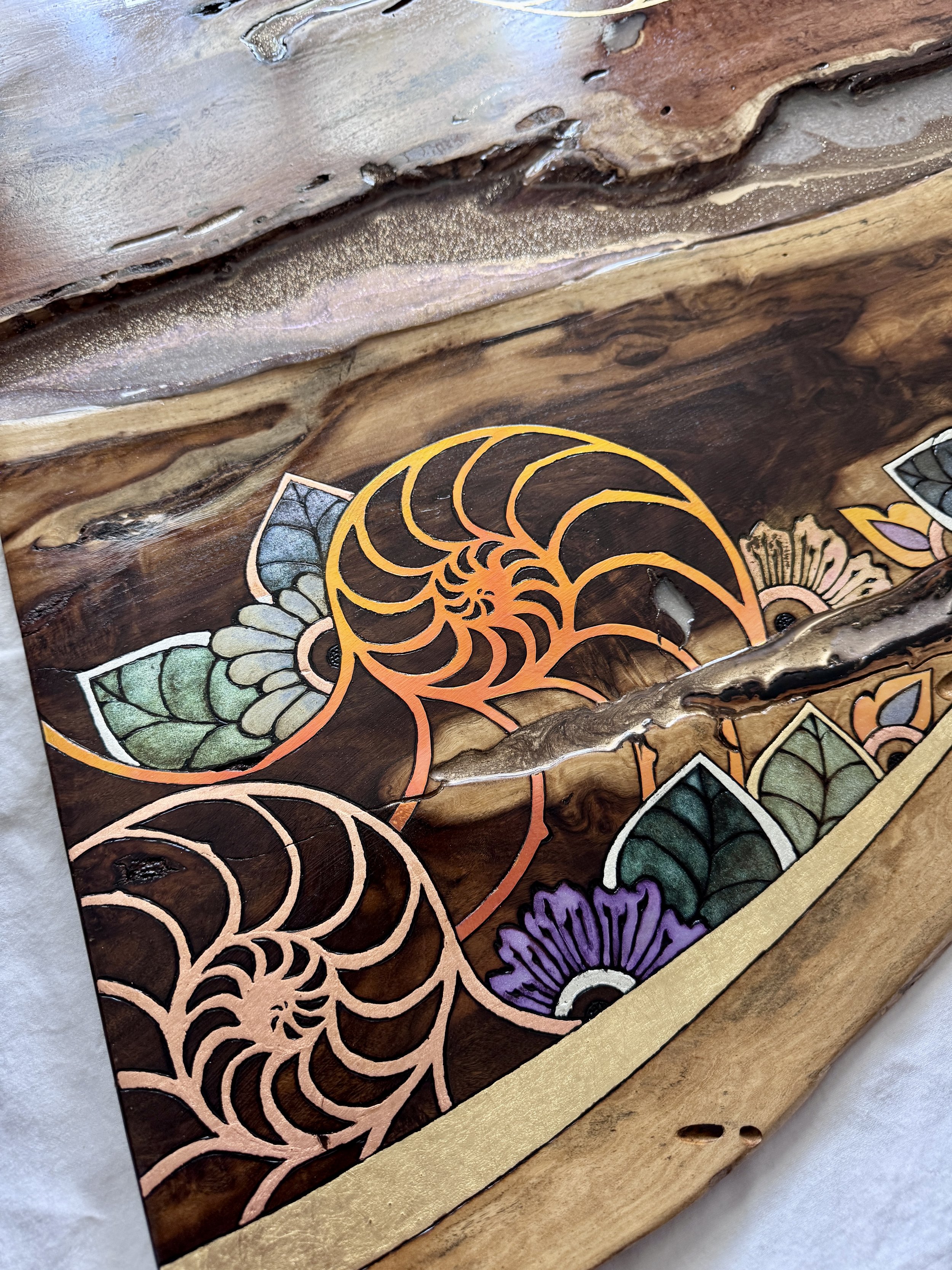 Detailed view of colorful pyrography patterns layered across Texas mesquite and maple with natural live edges.
