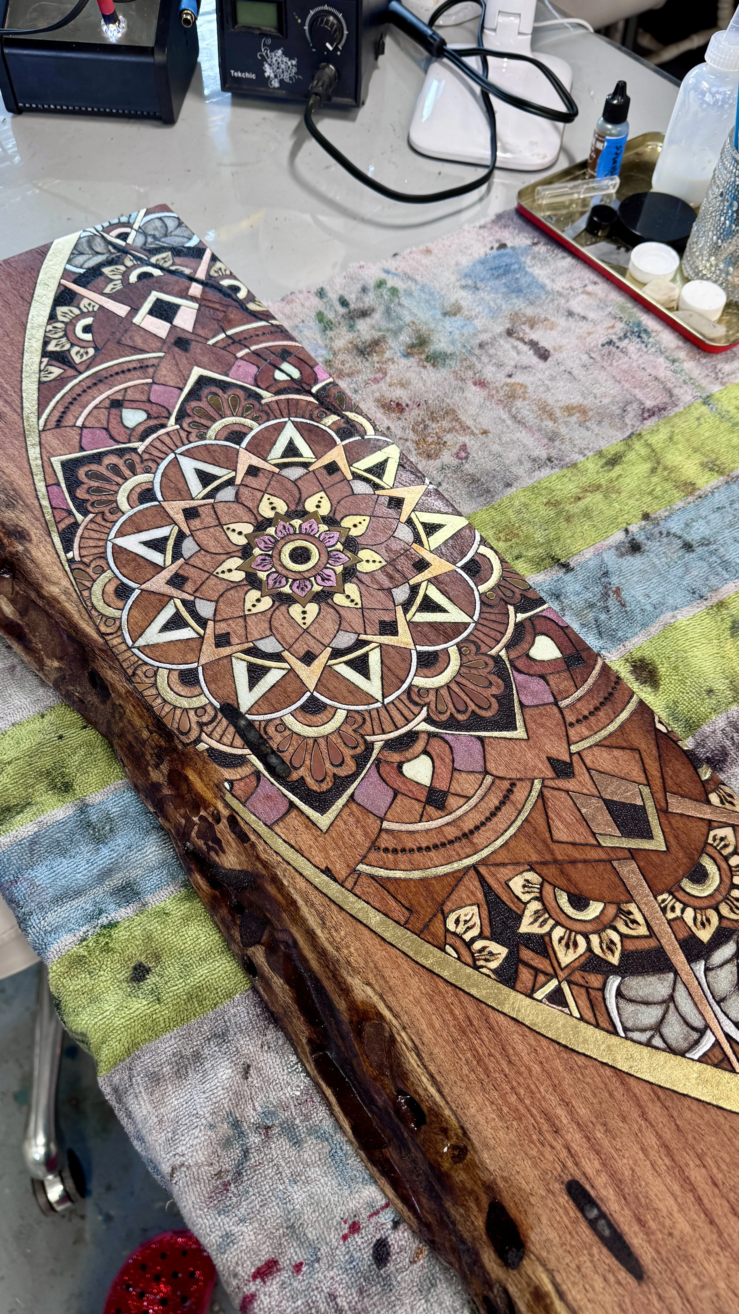 Close-up of pyrography detail with metal leaf on mesquite wood